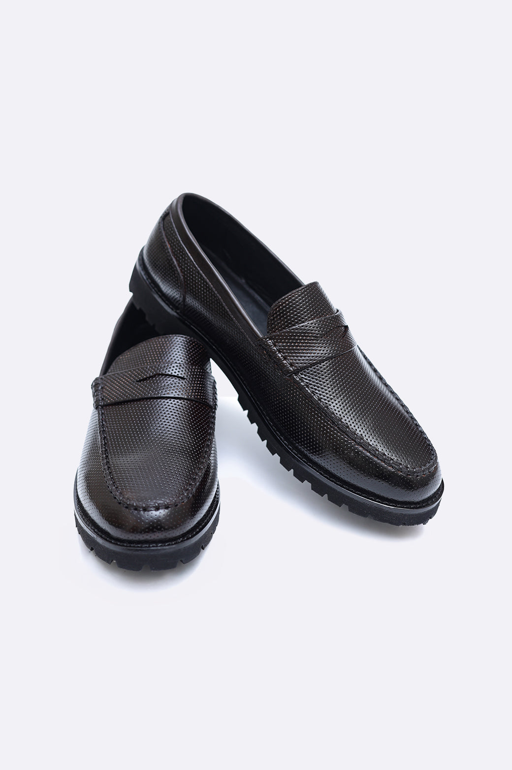 Pair of men's dark brown perforated leather penny loafers featuring a classic saddle strap and a thick black rugged lug sole.