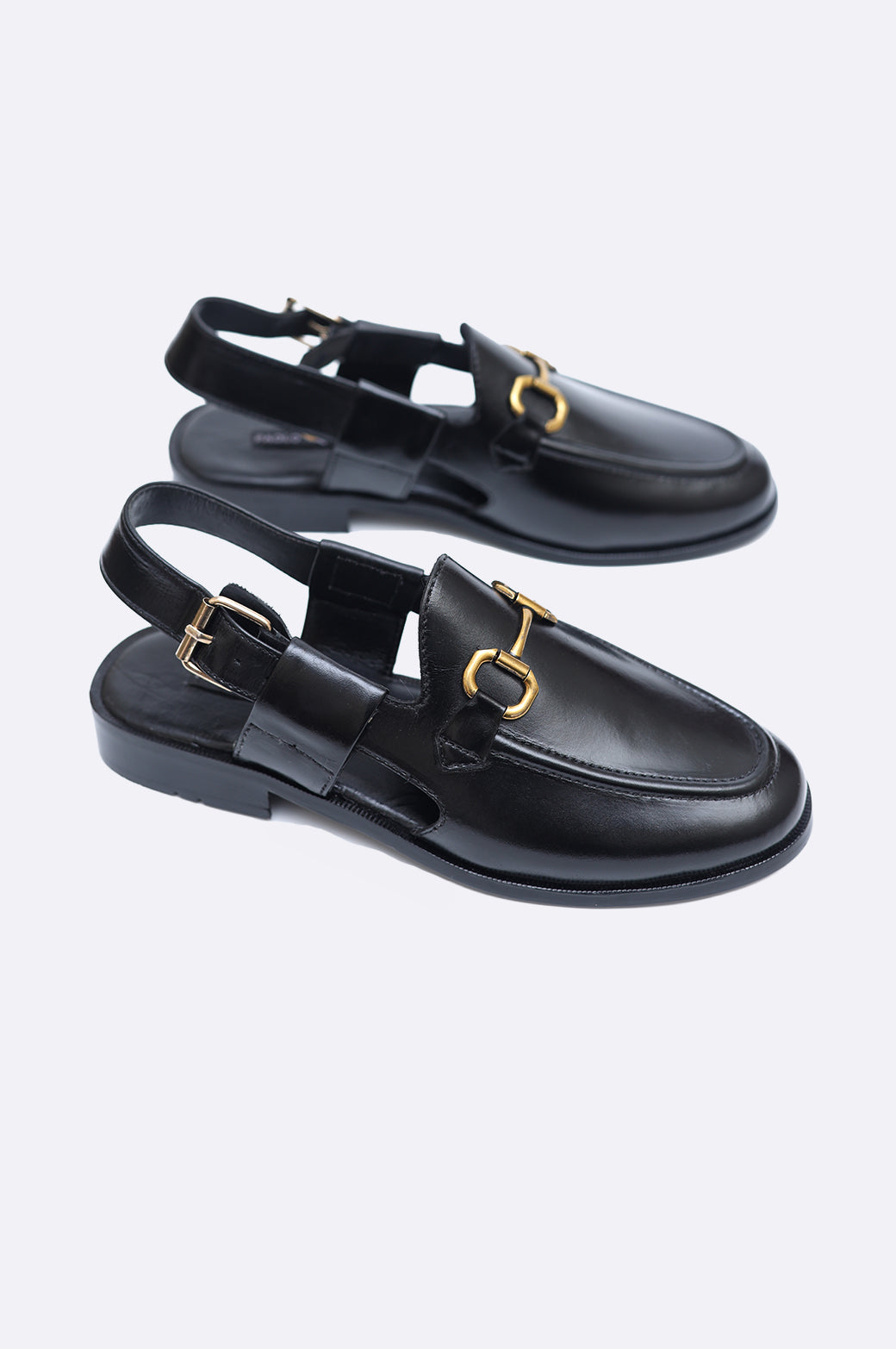 Pair of premium men's black leather closed-toe sandals with gold horsebit hardware and adjustable slingback heel straps.